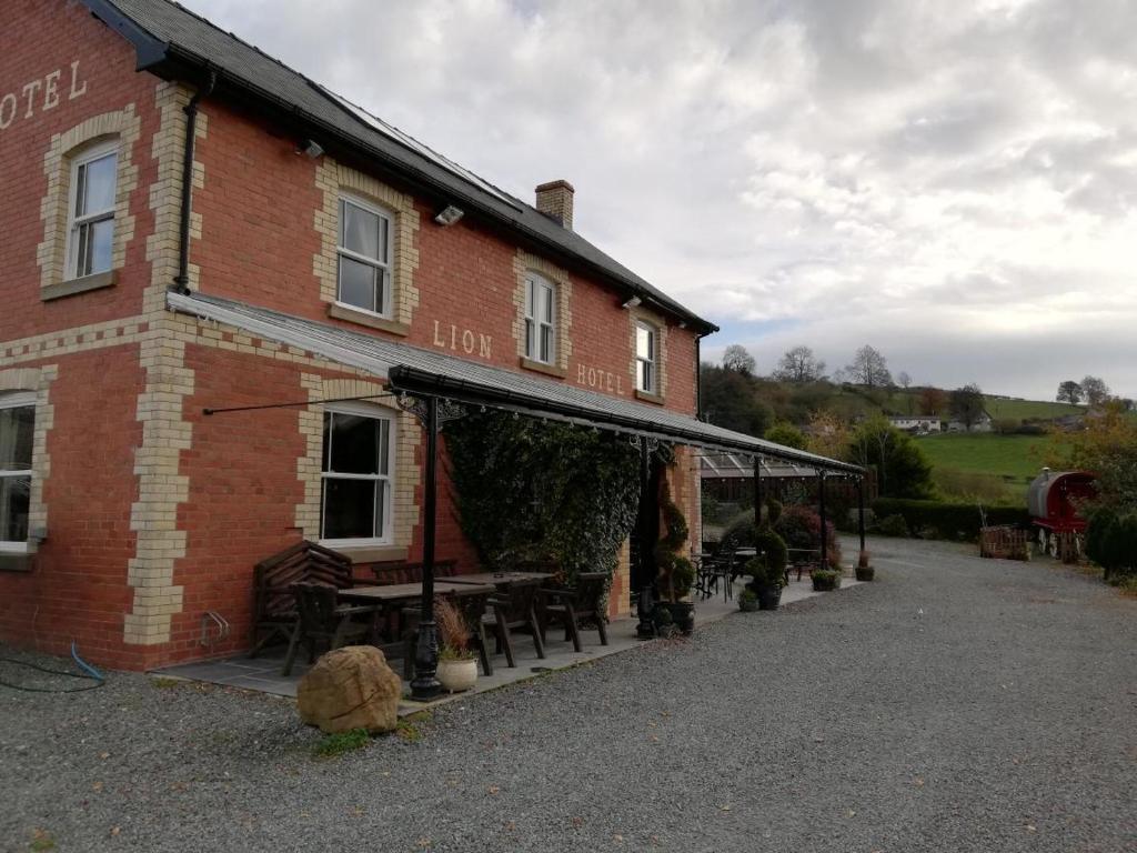 un bâtiment en briques avec des tables et des chaises devant lui dans l'établissement Lion Hotel, à Llanbister