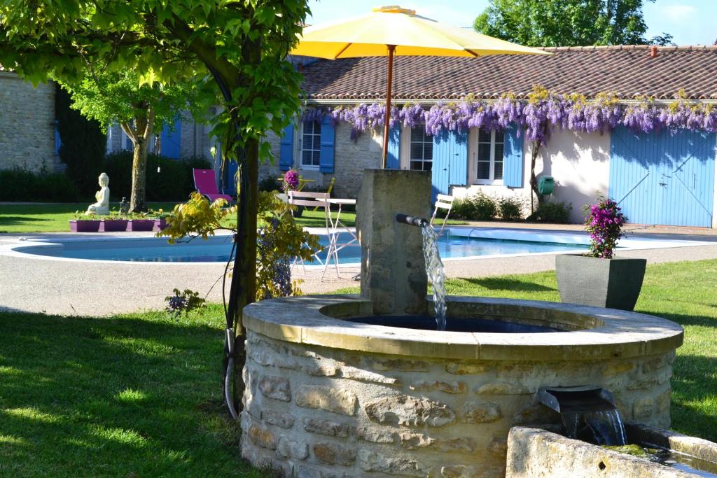 una fontana in pietra con un ombrello di fronte a una casa di L'instant bleu a Marans