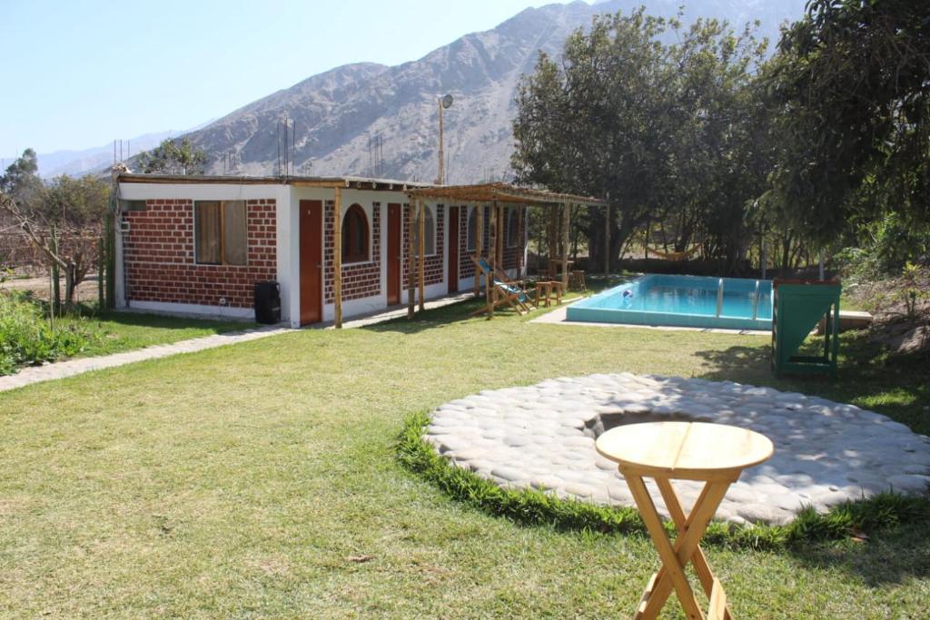 una casa con piscina y una mesa en el patio en Hotel Quilla Wasi, en Lunahuaná