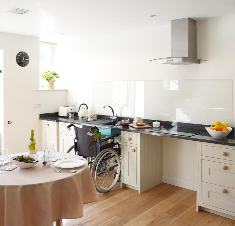 a kitchen with a wheelchair sitting next to a table at Manor Farm Courtyard Cottages in Hampstead Norris