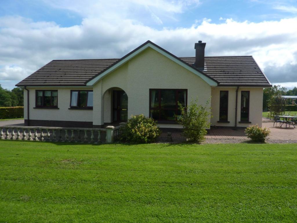 a small white house with a grass yard at Manorview B&B in Cookstown