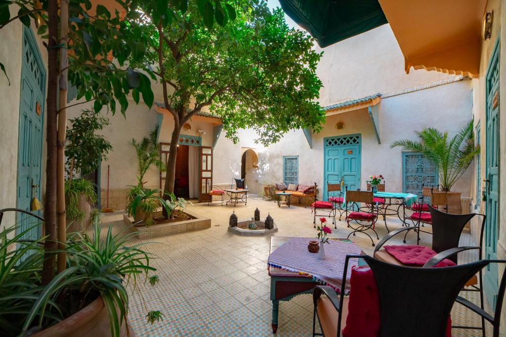 un patio al aire libre con mesas, sillas y plantas en Riad Dar Marhaba, en Marrakech