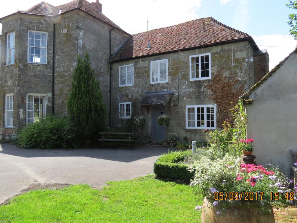 uma velha casa de pedra com um banco em frente em The Cottage Marshwood Farm em Dinton