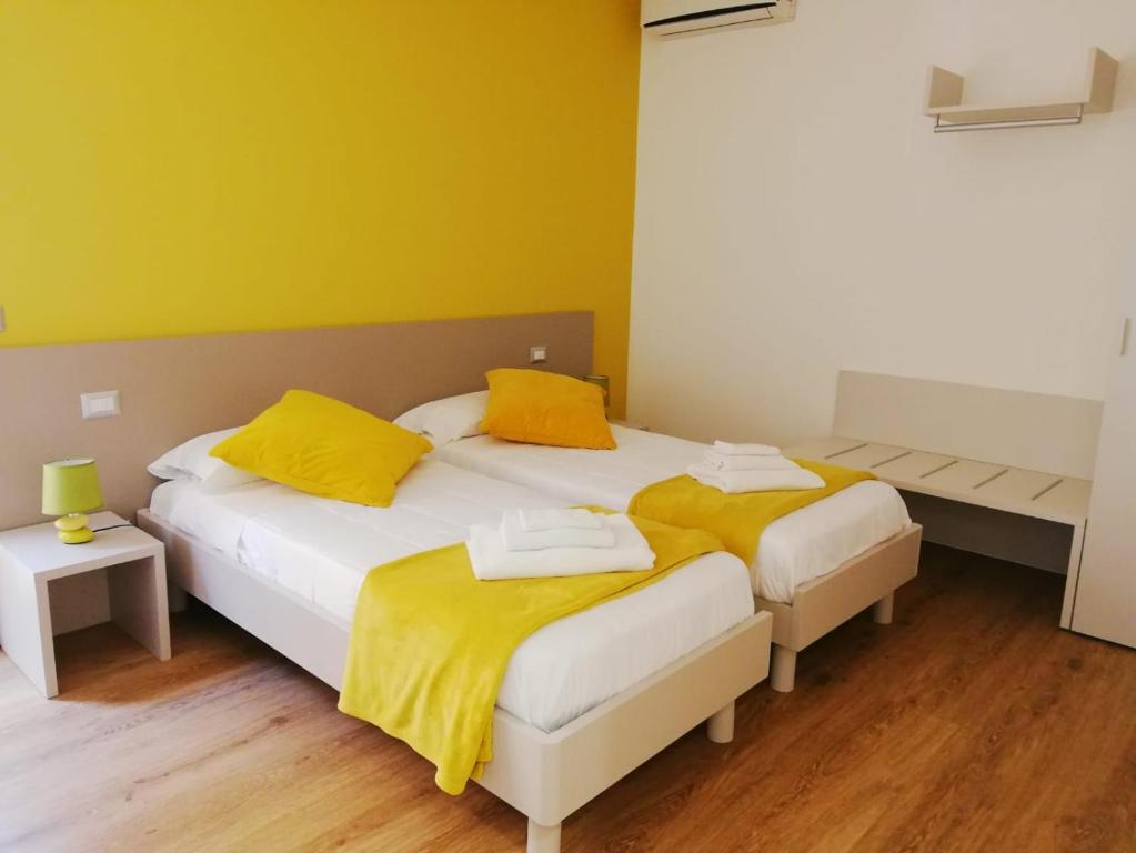 two beds in a room with yellow walls and wooden floors at HouseSandra Mare & Sole in Alghero