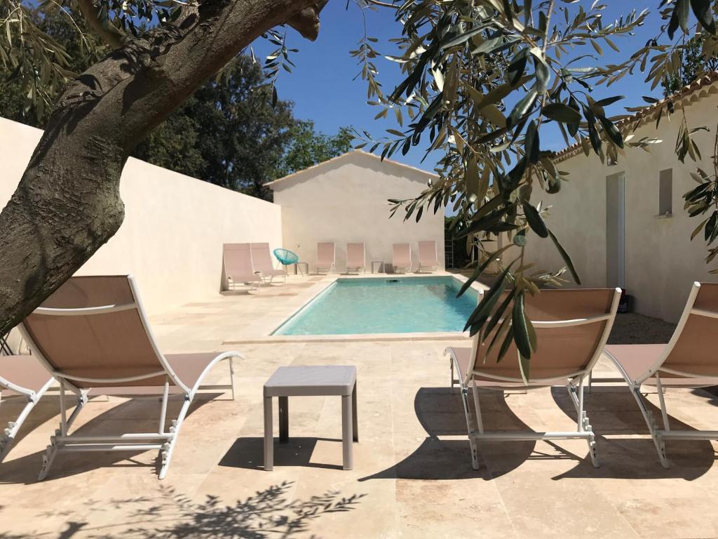 a pool with two chairs and a table and a tree at Les Mazets et Spa D'Uzes in Arpaillargues-et-Aureillac