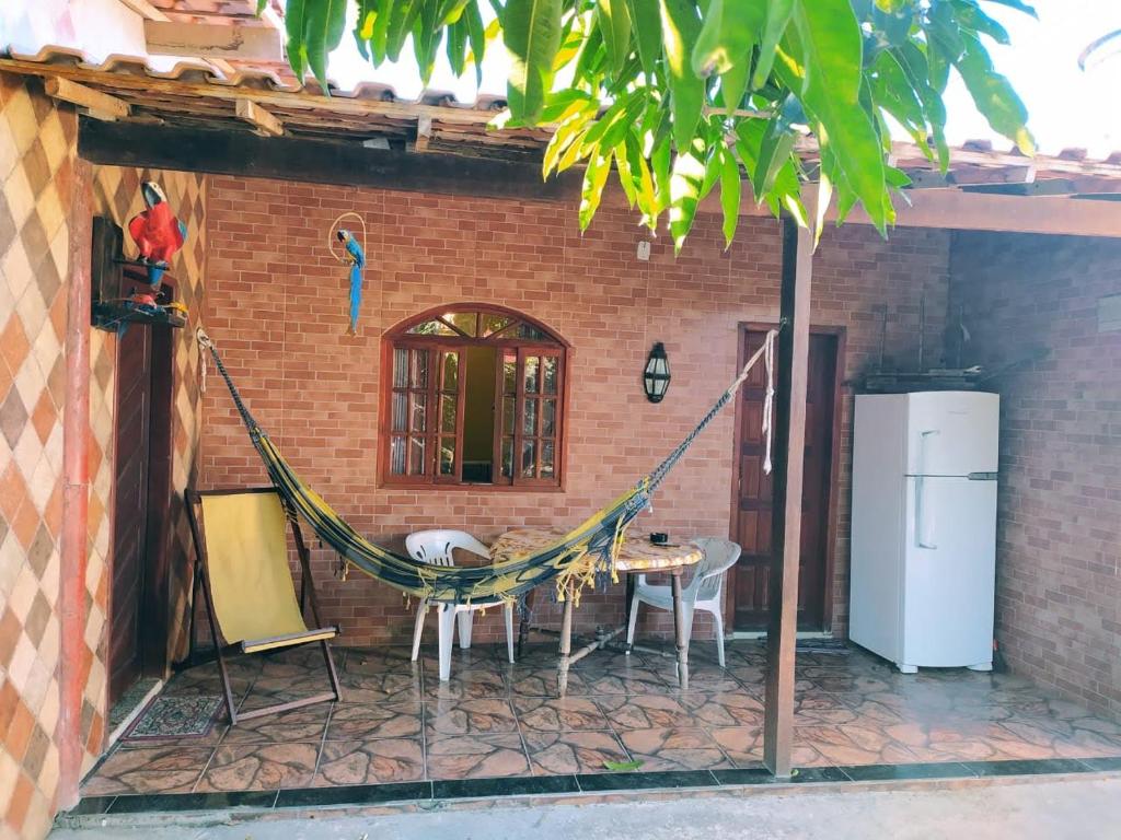 a patio with a hammock and a table and a refrigerator at Casa de praia completa em Cabo Frio - Melhor Custo x Benefício in Cabo Frio