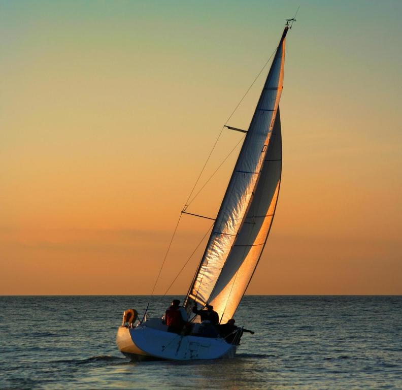 a sail boat in the ocean at sunset at Hotel Mare in Nazaré