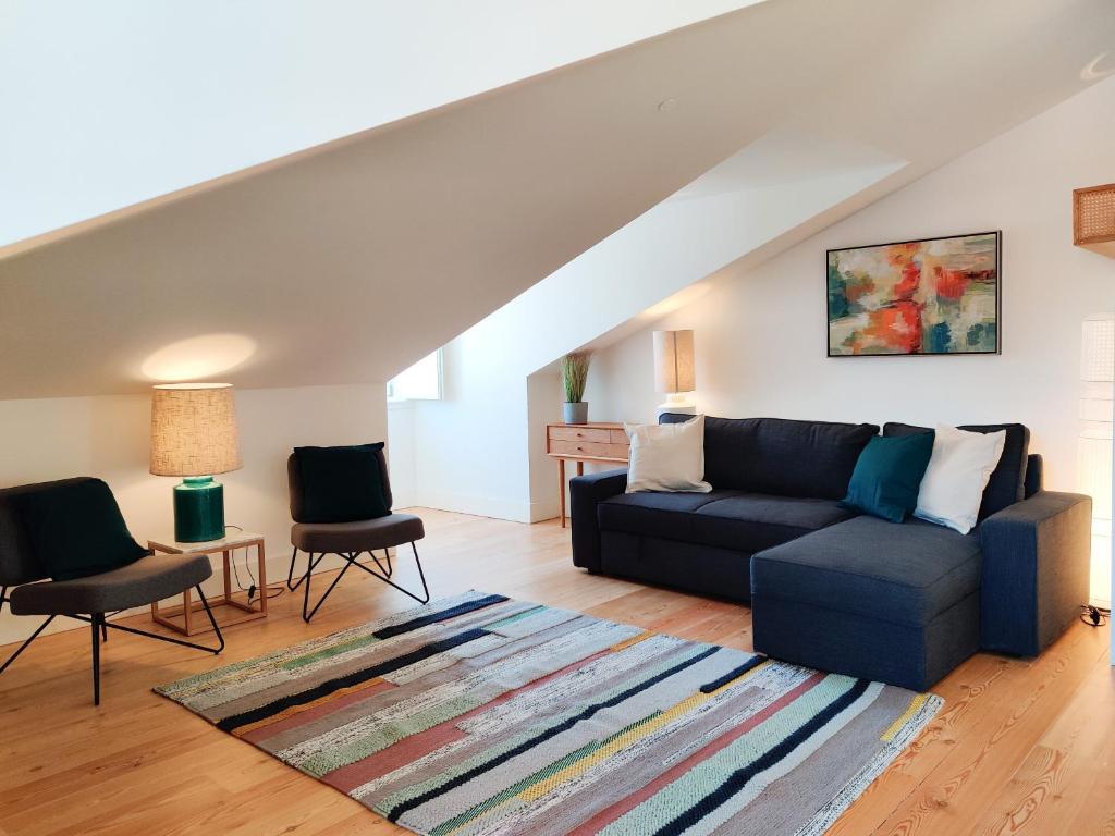 ein Wohnzimmer mit einem blauen Sofa und 2 Stühlen in der Unterkunft FLH Downtown Modern Apartment in Lissabon