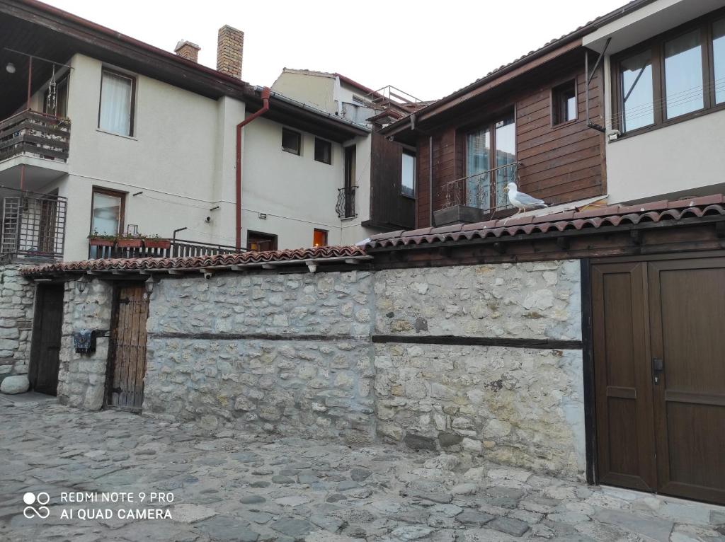 a stone wall next to a house and a building at Guest House Soirée in Nesebar