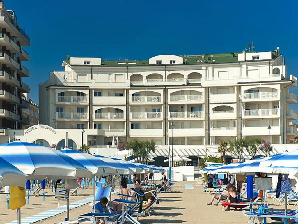 a building with blue and white umbrellas and people on the beach at Residence A-More in Rimini