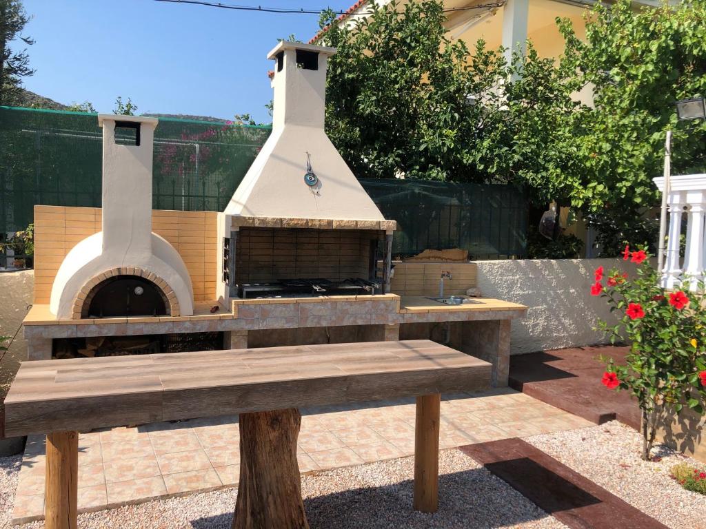 a outdoor pizza oven with a bench in a yard at Your Holiday House in Porto Rafti