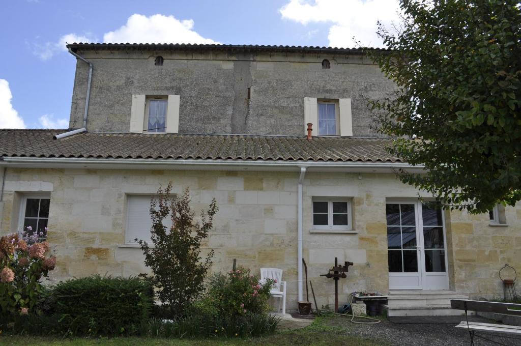 una vieja casa de piedra con una persona en el techo en Chambres d'Hotes La Mouline, en Ludon-Médoc