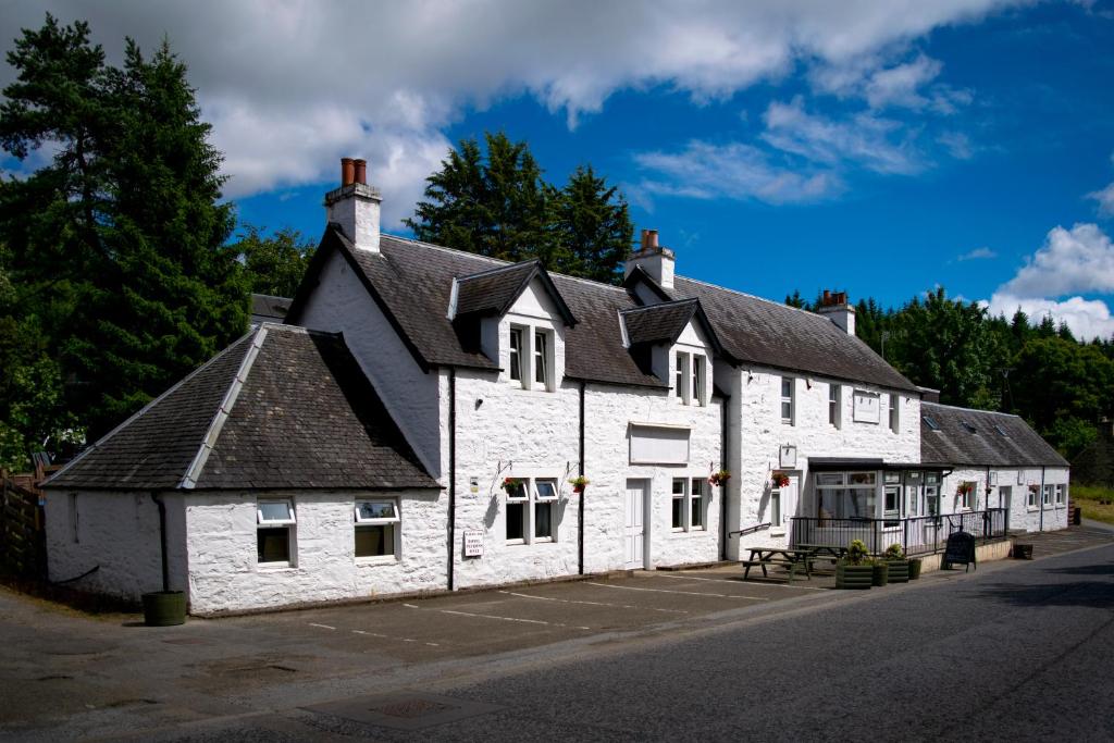 an old white building with a black roof at Ballinluig Rooms & Suites in Pitlochry