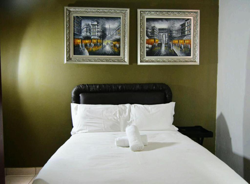 a white bed with two pictures on the wall at Bentley Lodge & Lifestyle in Durban