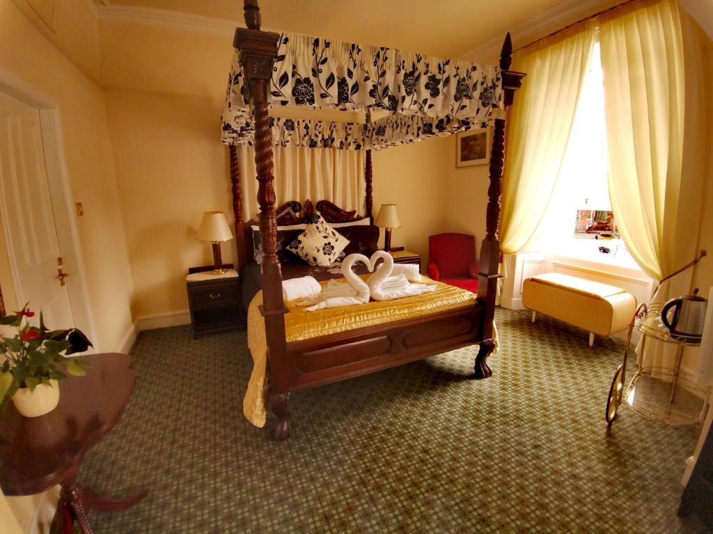 a bedroom with a canopy bed with swans on it at Victoria Hotel in Blairgowrie