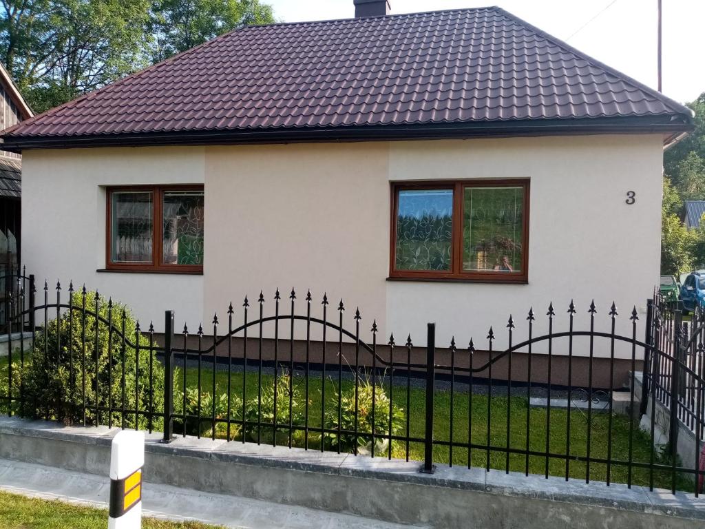 una cerca negra frente a una casa blanca en Domek en Reľov