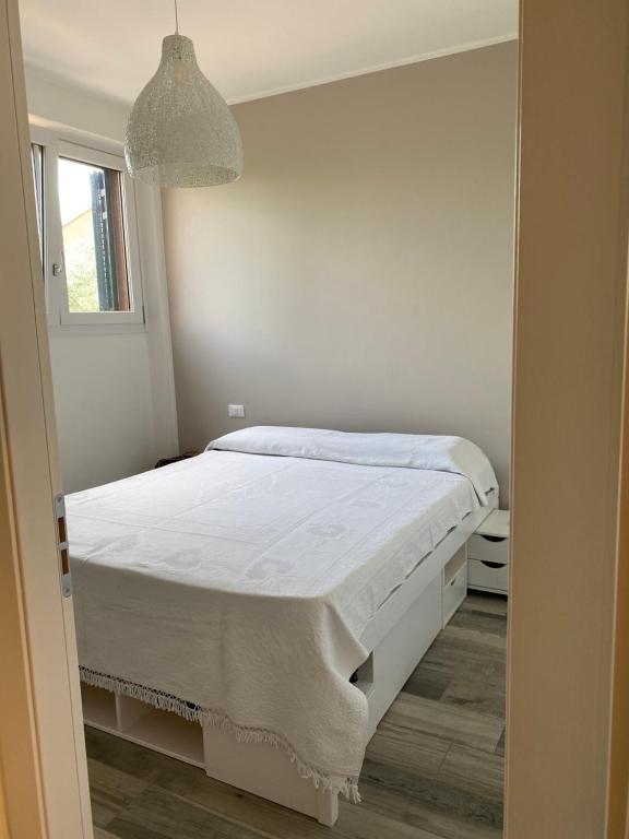 een witte slaapkamer met een bed en een raam bij Welcome Traveller APPARTAMENTO CASETTO in Bardolino