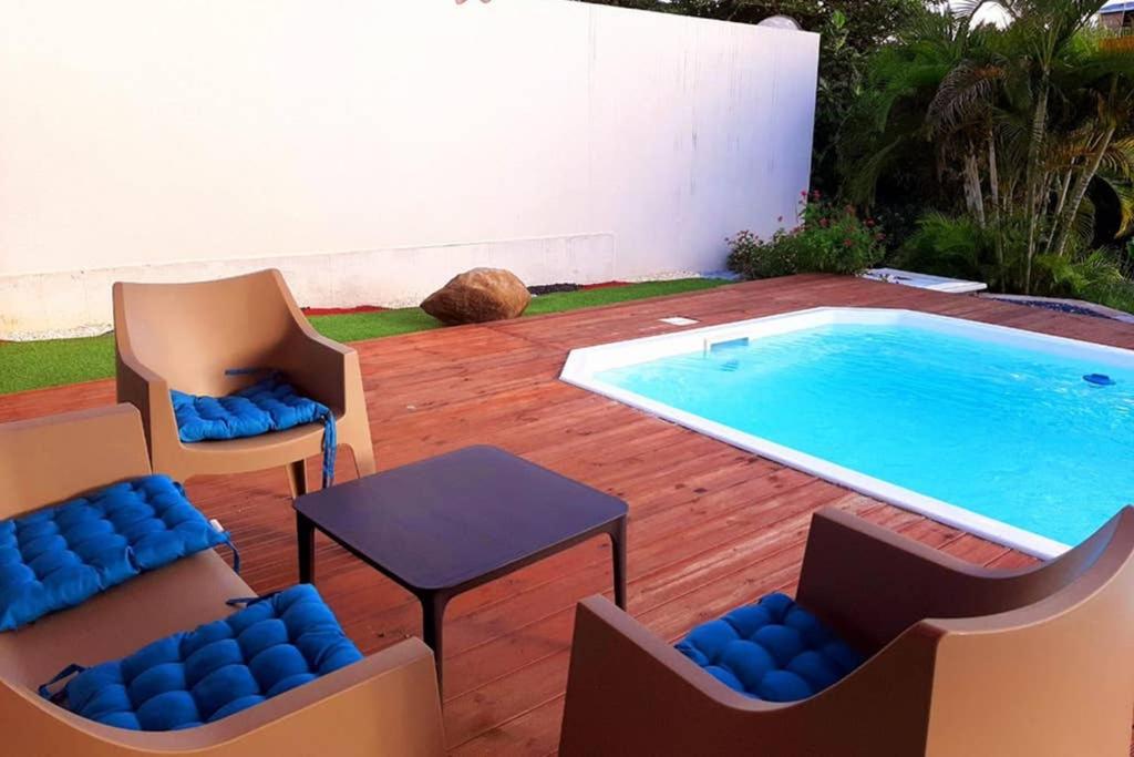 a patio with two chairs and a swimming pool at les orchidées in Petit-Bourg