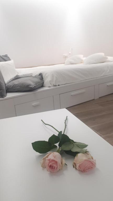 zwei Rosen auf einem weißen Tisch neben einem Bett in der Unterkunft cal dalmau apartaments loft in Pardines