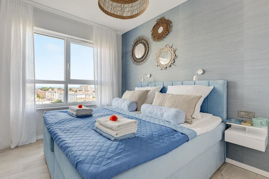 - une chambre bleue et blanche avec un lit et des serviettes dans l'établissement Baltica SeaView by TriApart, à Gdańsk