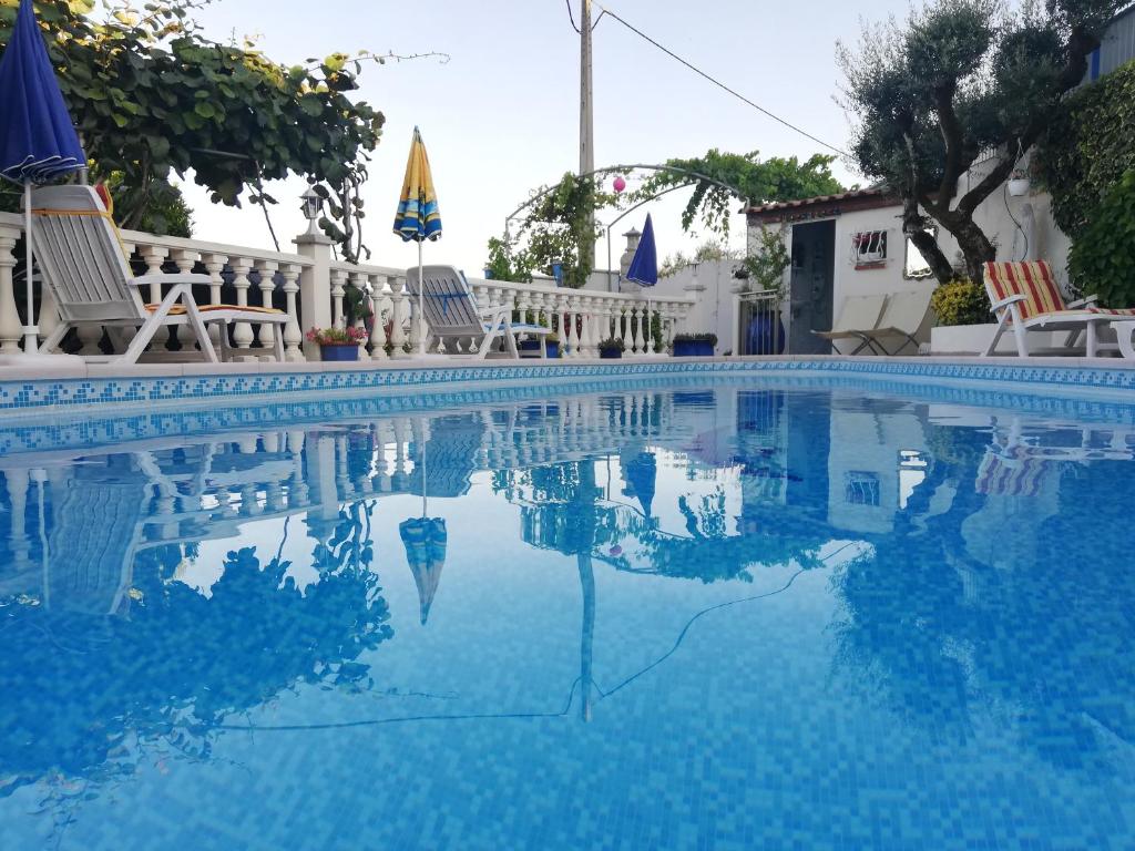 a large swimming pool with chairs and umbrellas at Vivenda Soares in Fátima