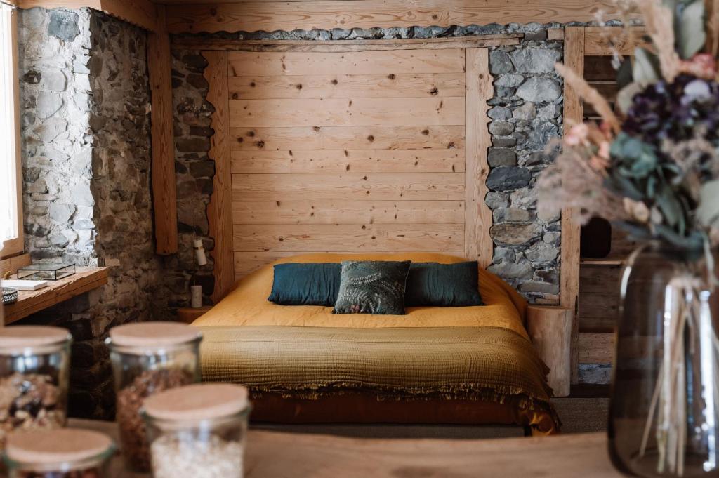 a bedroom with a bed with a stone wall at l'Herbier - chambre d'Hôtes - in Marnaz