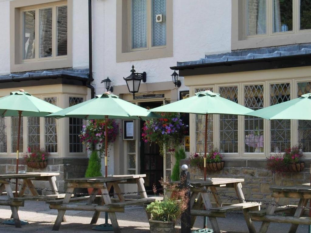 a group of picnic tables with umbrellas in front of a building at The Miners Arms in Eyam