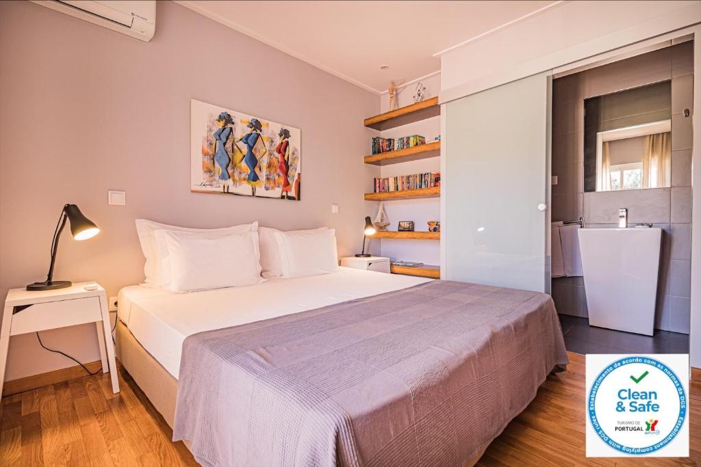 a small bedroom with a bed and a refrigerator at Buganvilias Do Meco Guest house in Sesimbra