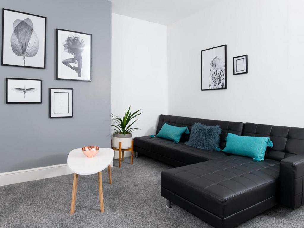 uma sala de estar com um sofá preto e uma mesa em MyUKSuites em Hull