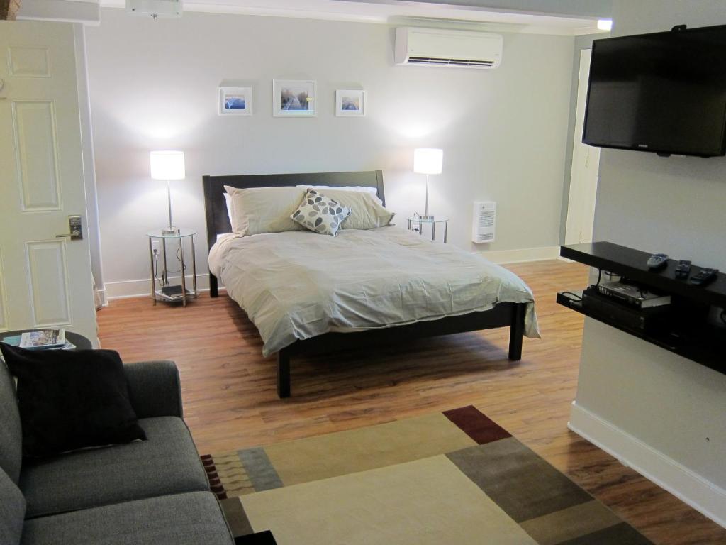 1 dormitorio con cama, sofá y TV en Merrickville Guest Suites en Merrickville