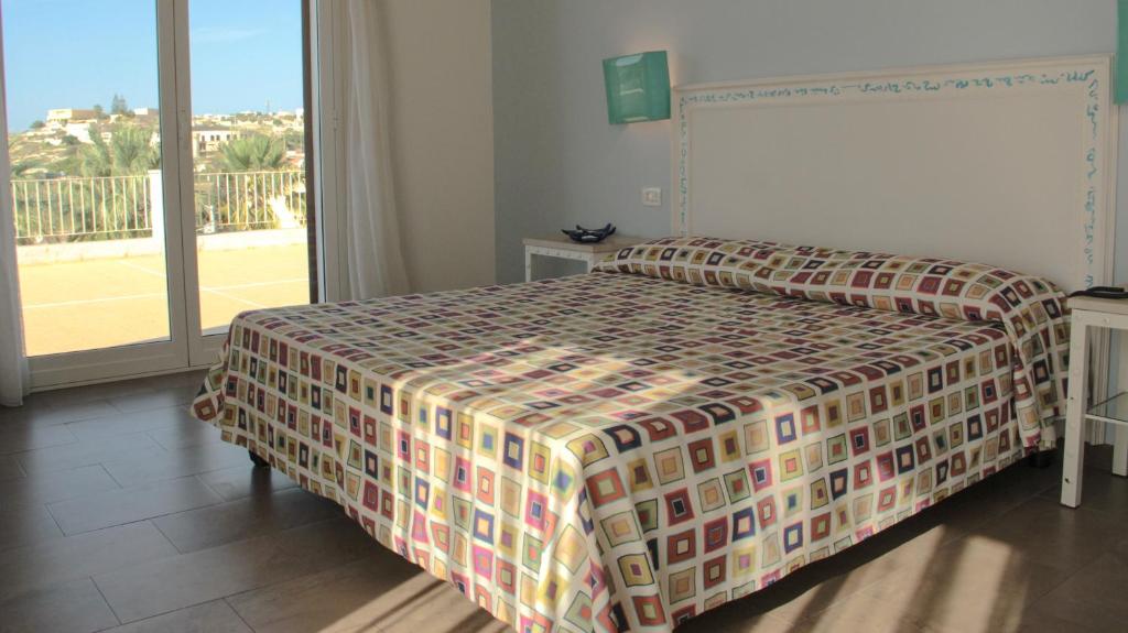 a bedroom with a bed and a large window at Hotel O'scià in Lampedusa