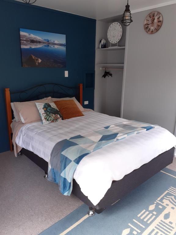 um quarto com uma cama grande e paredes azuis em J&D Cottage em Kerikeri