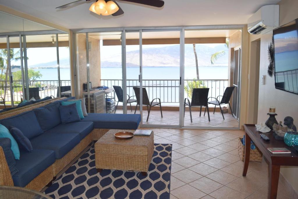 uma sala de estar com um sofá azul e vista para o oceano em Menehune Shores 309 em Kihei