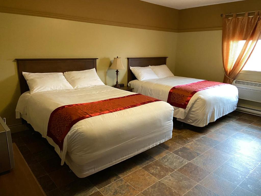 two beds in a hotel room with at Motel le Phare in Plessisville