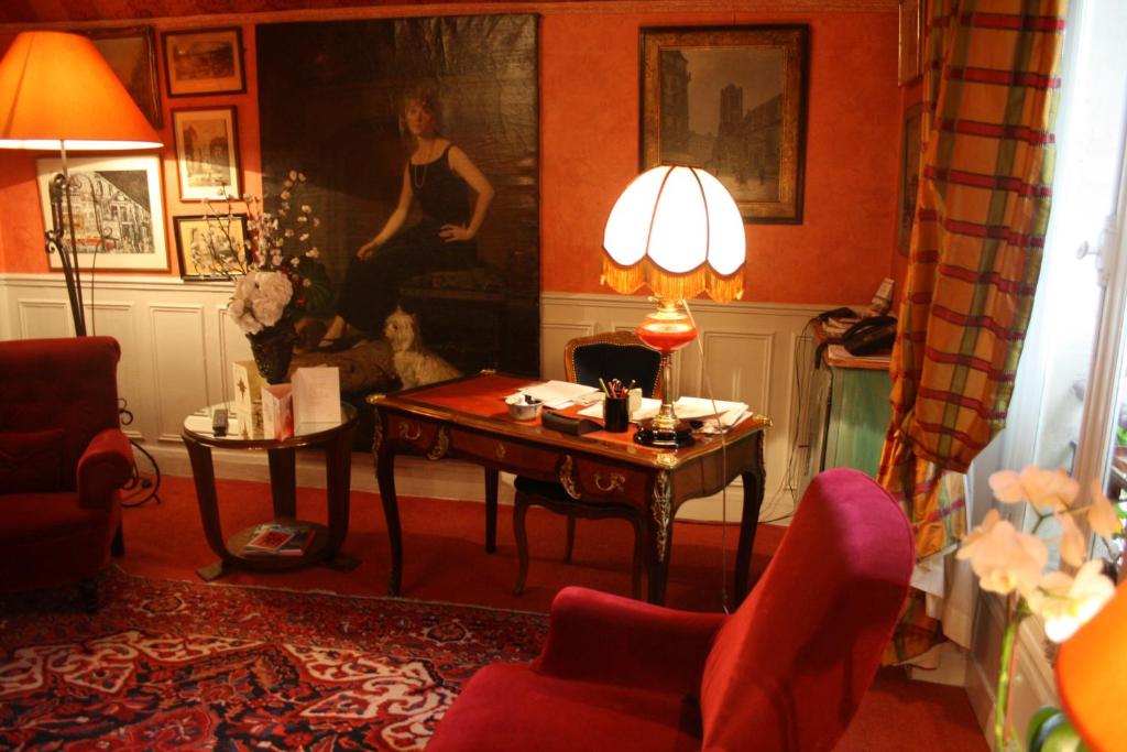 uma sala de estar com uma mesa com um candeeiro e cadeiras em Hôtel De Nice em Paris