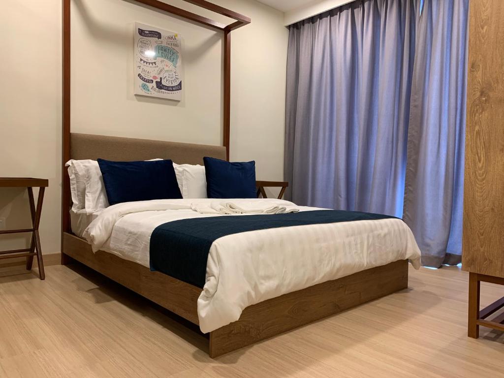 - une chambre avec un grand lit et des rideaux bleus dans l'établissement Timurbay Seaview Suite by Guns Studio, à Kuantan