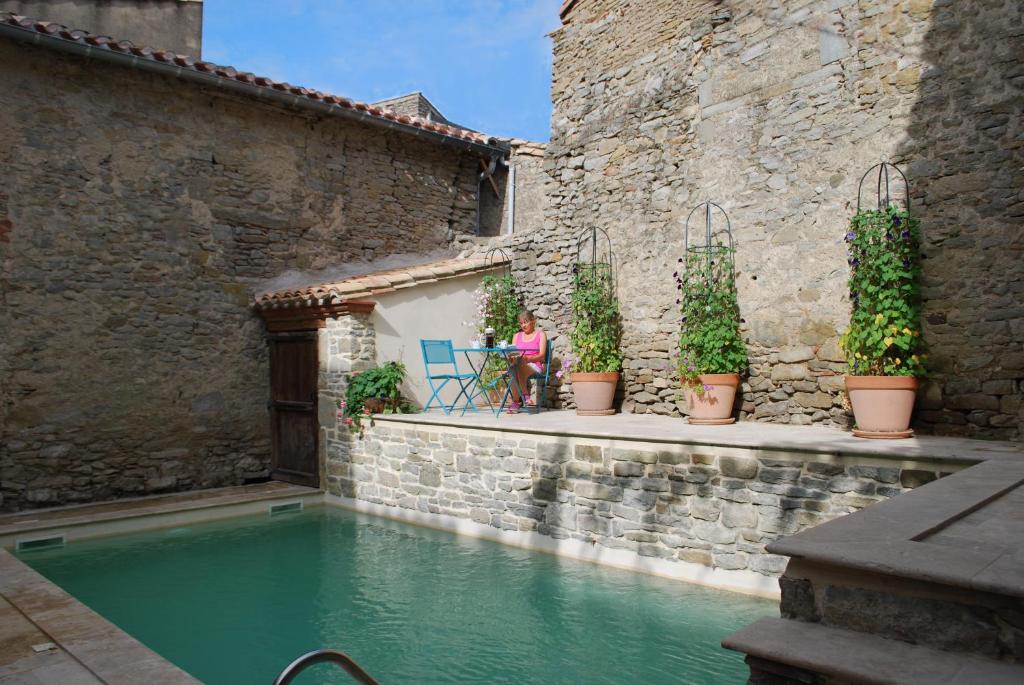 a woman sitting at a table next to a swimming pool at La Sentinelle in Siran