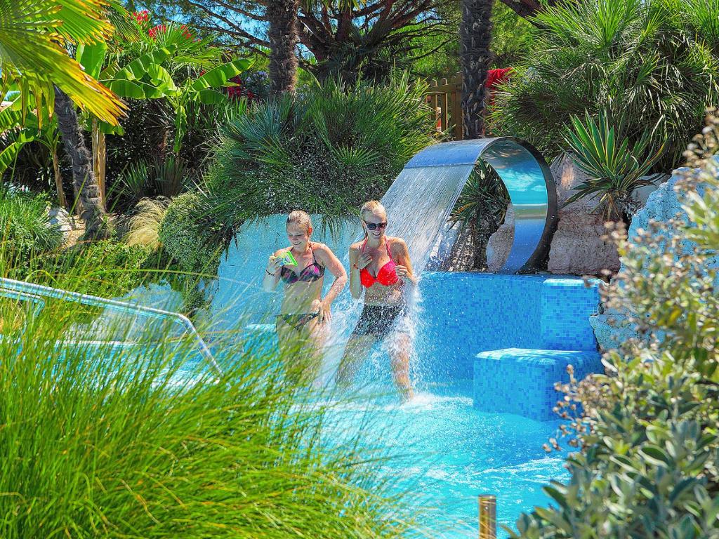 two people are playing in a pool in a resort at Portofelice Camping Village in Eraclea Mare