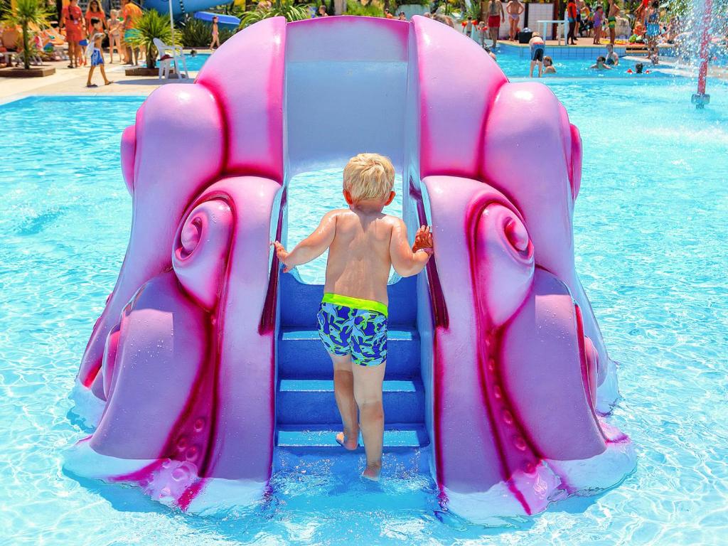 a young boy going down a water slide at a water park at Portofelice Camping Village in Eraclea Mare