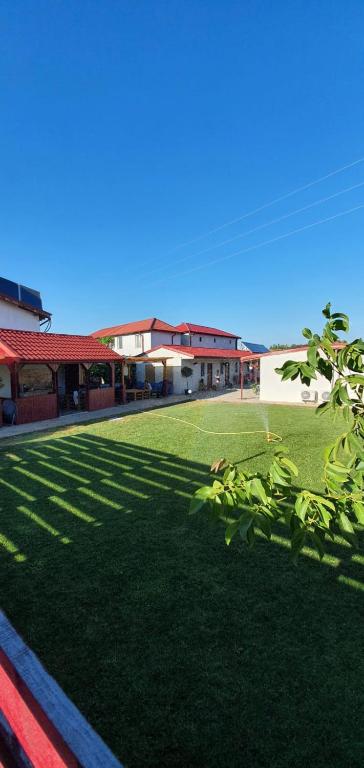 a green yard with a building and shadows on it at Pagini Din Vama in Vama Veche