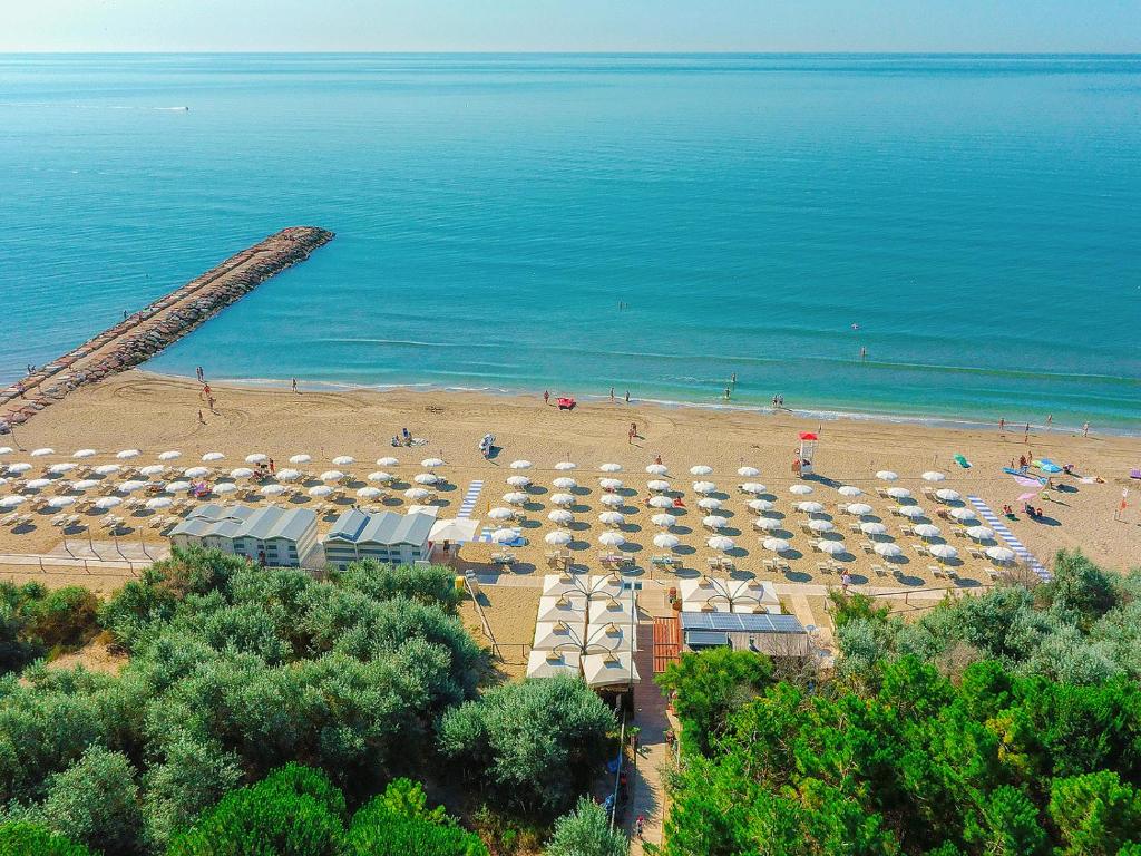 a beach with a lot of umbrellas and people on it at Portofelice Camping Village in Eraclea Mare