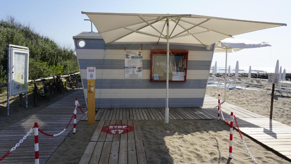 a small building on the beach with an umbrella at Portofelice Camping Village in Eraclea Mare