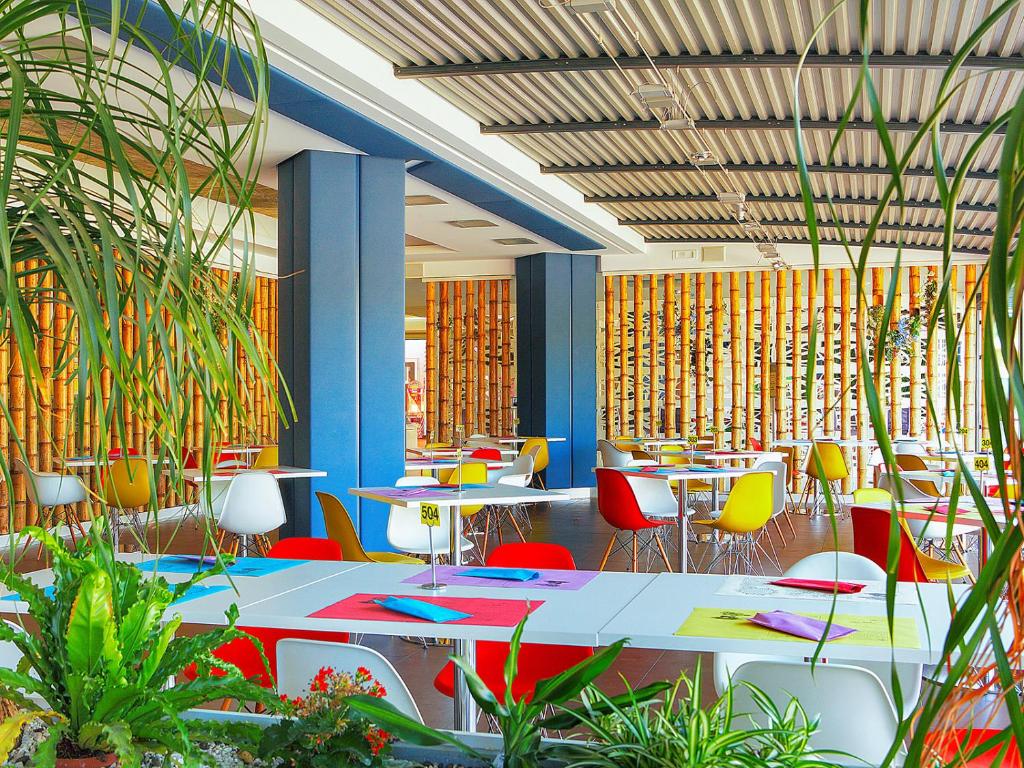 a restaurant with tables and colorful chairs and plants at Portofelice Camping Village in Eraclea Mare