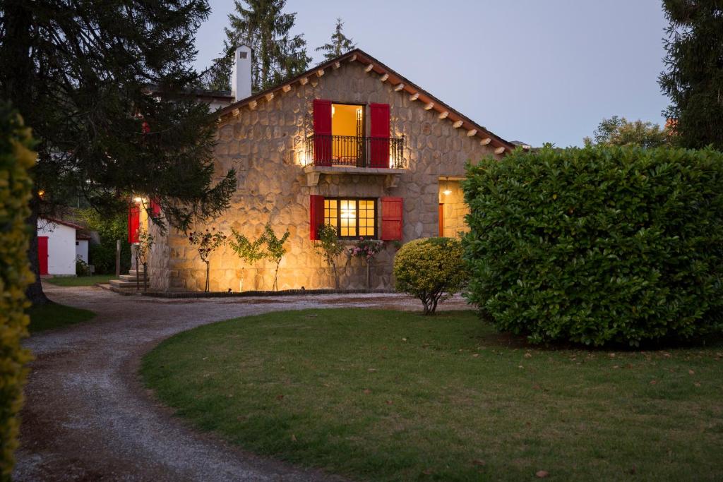 a stone house with red windows and a yard at CHALET EN PLAYA DE CABAÑAS in Cabañas