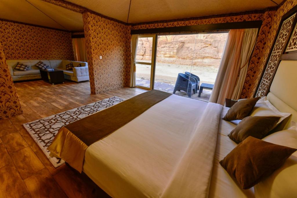 a bedroom with a large bed with a large window at Sahary Al Ula Resort in AlUla
