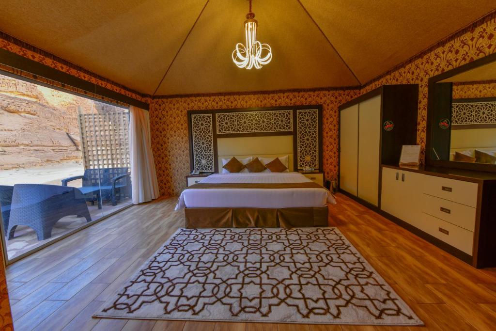 a bedroom with a bed and a large window at Sahary Al Ula Resort in AlUla