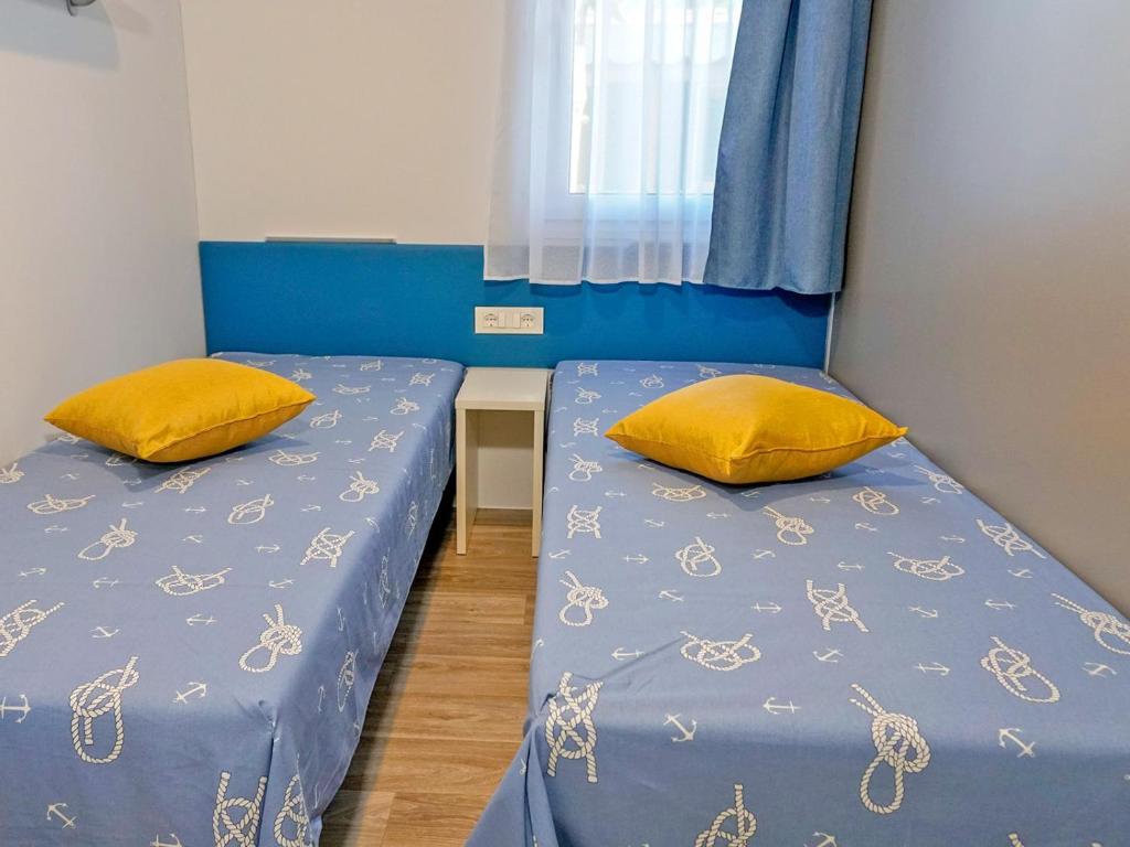 two beds with yellow pillows in a room at Portofelice Camping Village in Eraclea Mare