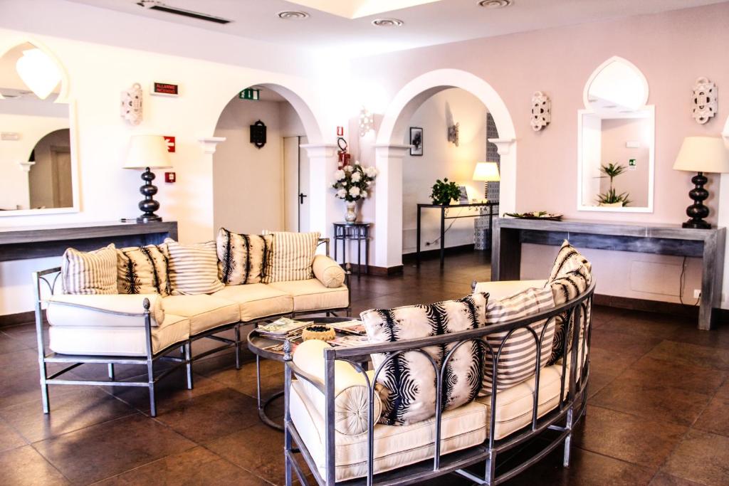 a lobby with couches and a table and mirrors at Hotel O'scià in Lampedusa