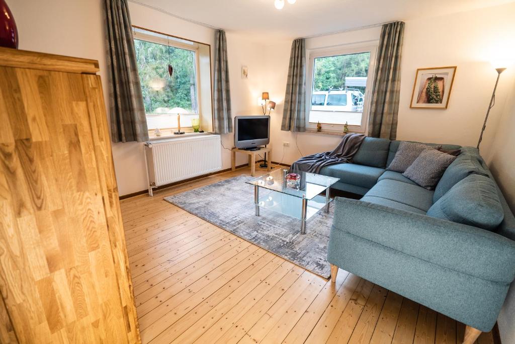 a living room with a blue couch and a tv at Ferienwohnung im Ottenhai (EG) in Bad Harzburg