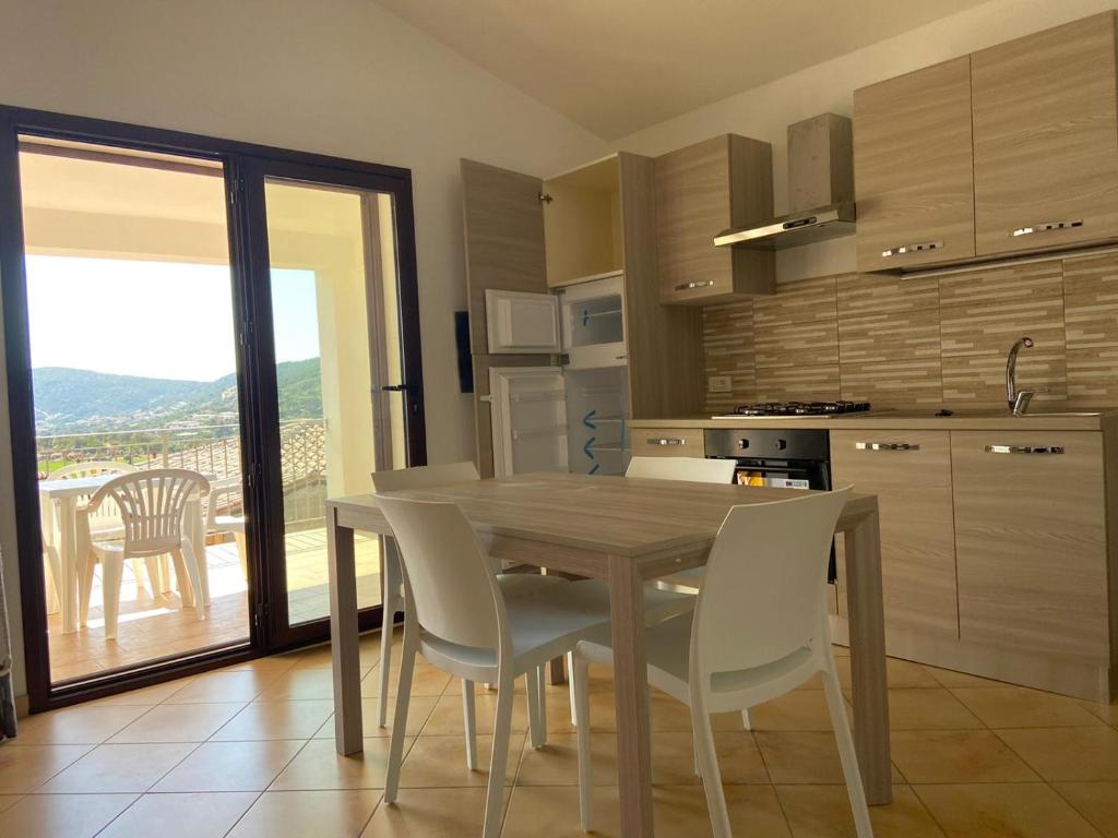 eine Küche mit einem Holztisch und weißen Stühlen in der Unterkunft Le Villette di Budoni e dintorni in Budoni